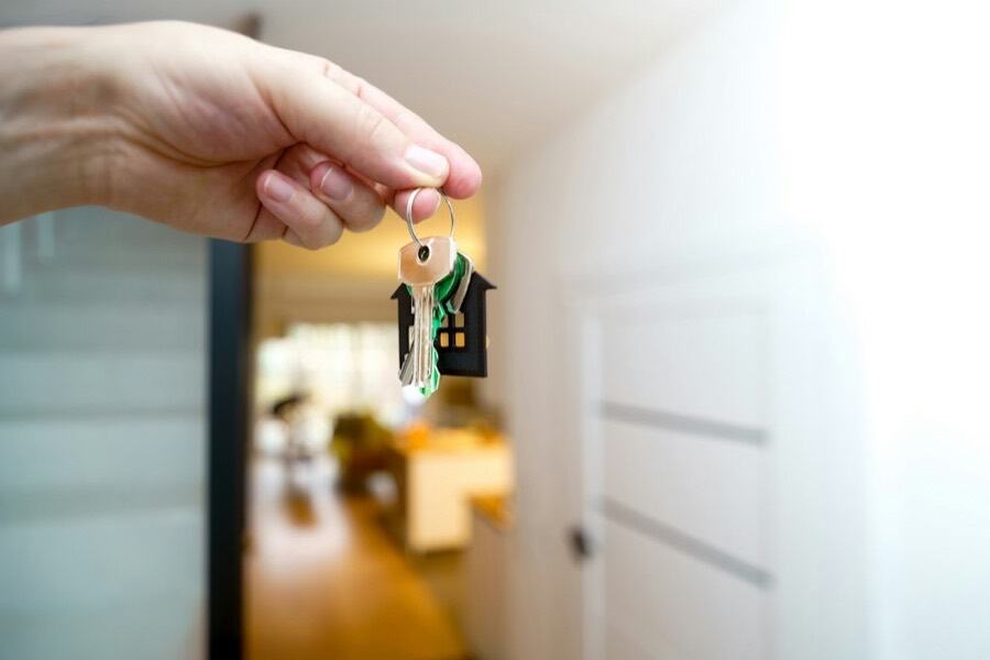 Hand holding house keys at a front door